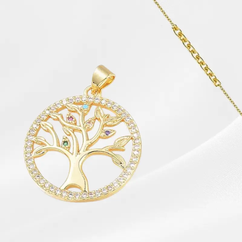 Pendentif Arbre de vie 1 Pendentif Arbre de Vie en acier inoxydable plaqué or, médaillon rond ajouré avec un arbre stylisé aux branches ornées de zircons multicolores (turquoise, rose, mauve, vert) et un contour serti de zircons blancs, suspendu à une fine chaîne dorée forçat, photographié sur fond blanc satiné.