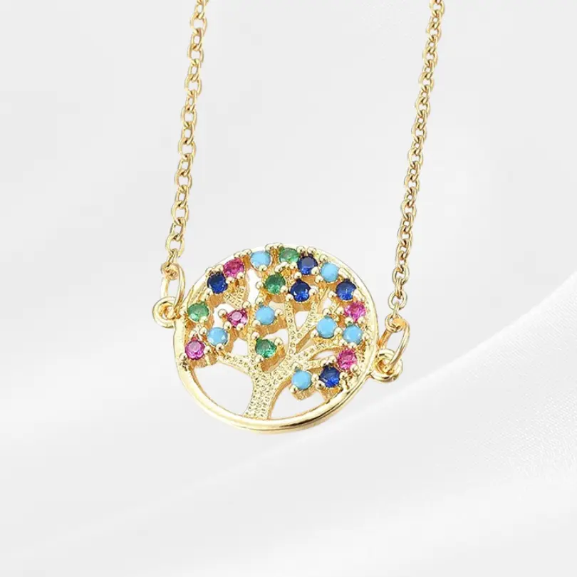 Pendentif Arbre de vie 7 Collier Arbre de Vie en acier inoxydable plaqué or, médaillon rond ajouré fixé latéralement sur une chaîne forçat dorée traversante, avec un arbre aux branches texturées orné de grands zircons ronds multicolores (bleu saphir, turquoise, rose fuchsia, vert émeraude, orange) répartis en couronne dense sur les branches, photographié à plat sur fond blanc satiné.
