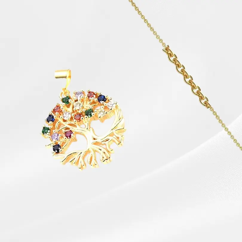 Pendentif Arbre de vie 4 Pendentif Arbre de Vie en acier inoxydable plaqué or, médaillon rond ajouré sans bordure, avec un arbre aux racines apparentes et une couronne dense de zircons ronds multicolores (bleu, vert, mauve, orange, rouge, blanc) serties en grappe sur les branches, suspendu à une fine chaîne dorée forçat, photographié en léger biais sur fond gris clair satiné.
