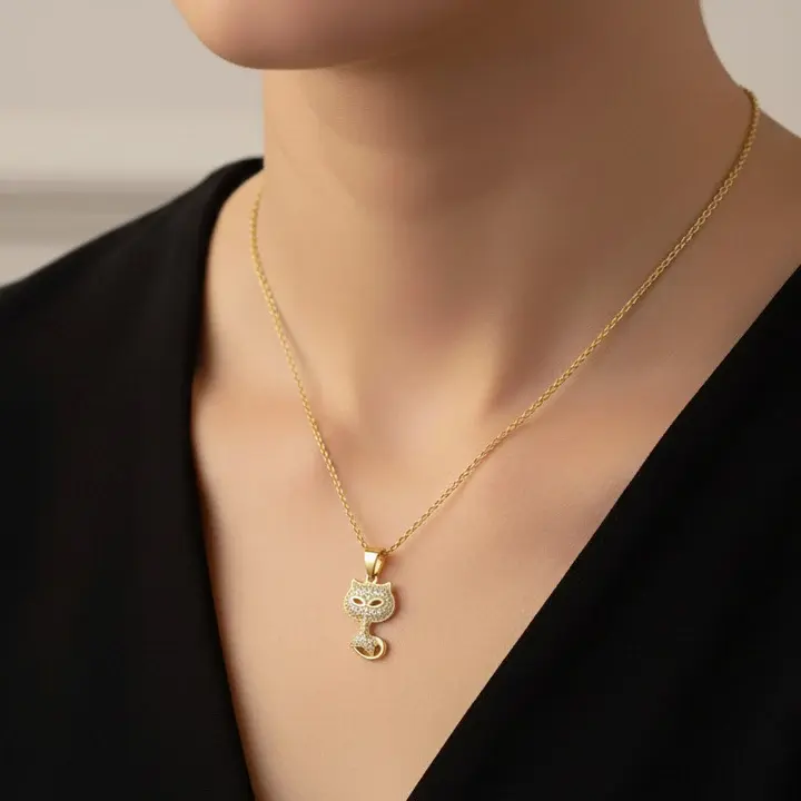 Pendentif Chat 3 Femme portant un collier pendentif chat plaqué or pavé de zirconiums scintillants, chaîne dorée fine au décolleté – bijou fantaisie tendance