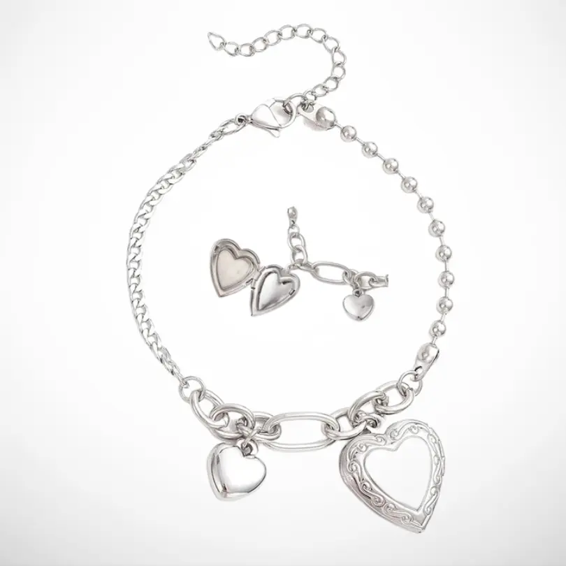 Bracelet Femme Photo 1 Bracelet femme photo en acier inoxydable argenté avec deux pendentifs cœur, dont un médaillon cœur ouvrant porte-photo gravé et un cœur lisse, sur chaîne maillons et billes, fond blanc