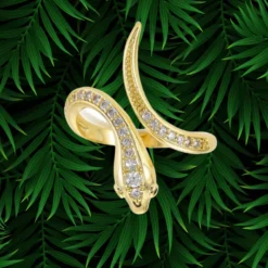 Bague Serpent Femme 13 Bague serpent femme dorée plaquée or, corps allongé en X serti d'une ligne de zirconiums blancs, tête centrale détaillée, anneau ouvert ajustable, bijou serpent statement sur fond de palmier