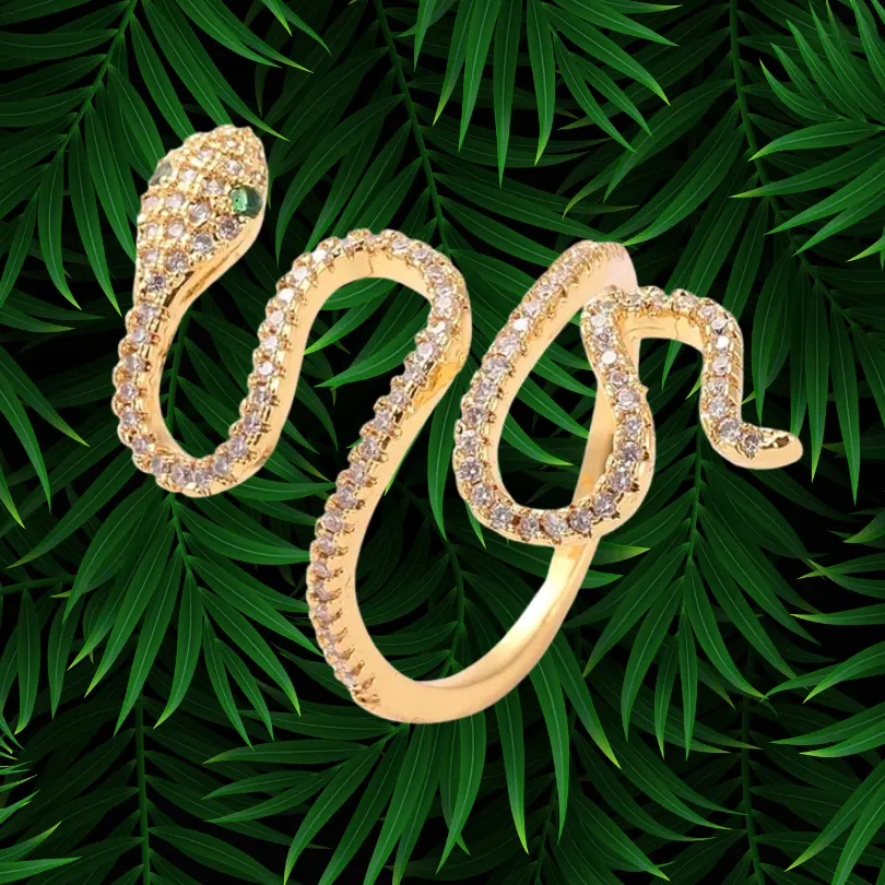 Bague Serpent Femme 1 Bague serpent femme plaquée or ornée de zircons blancs scintillants et d'yeux en pierre verte, bijou ajustable tendance sur fond de feuillage tropical