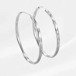 Boucles d'oreilles Créoles Argent 925 Judith , anneaux ronds 50 mm à facettes ciselées, bijou féminin sobre sur fond blanc