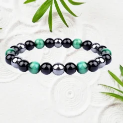 Bracelet obsidienne et œil de tigre vert, perles rondes noires, vertes et hématite 6 mm sur élastique, fond blanc texturé avec feuilles — bijou pierre naturelle homme femme