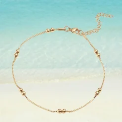 Chaîne de cheville dorée en acier inoxydable avec perles rondes lisses dorées, maille vénitienne fine, fermoir mousqueton ajustable, fond plage