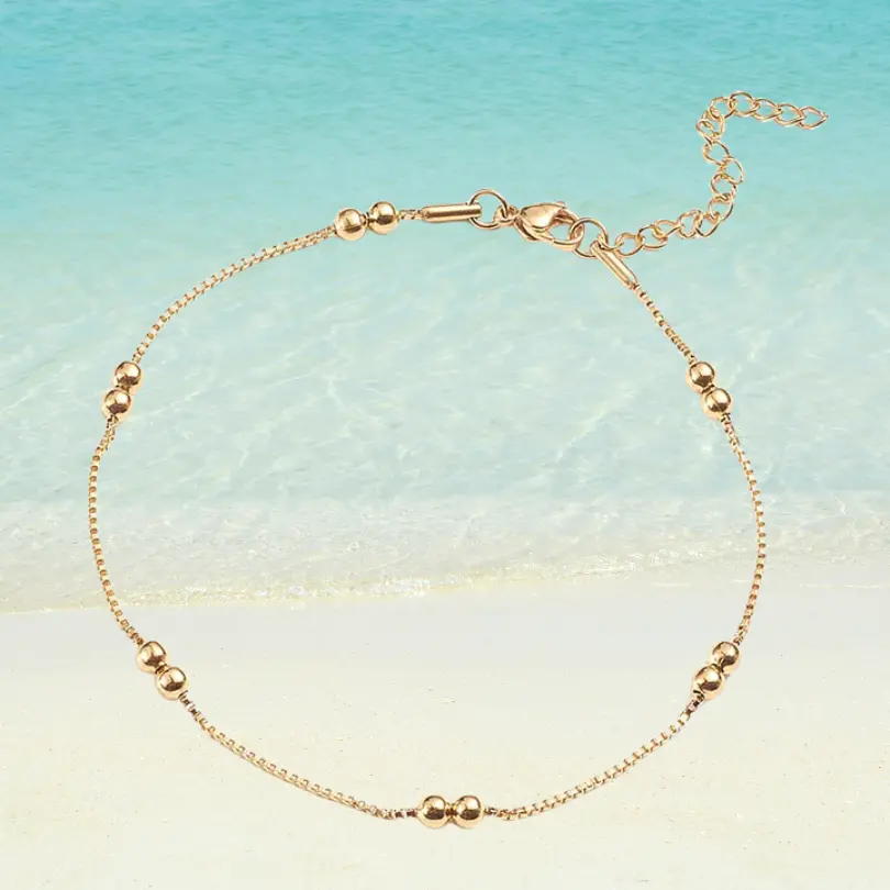 Chaîne de Cheville Perle 2 Chaîne de cheville dorée en acier inoxydable avec perles rondes lisses dorées, maille vénitienne fine, fermoir mousqueton ajustable, fond plage
