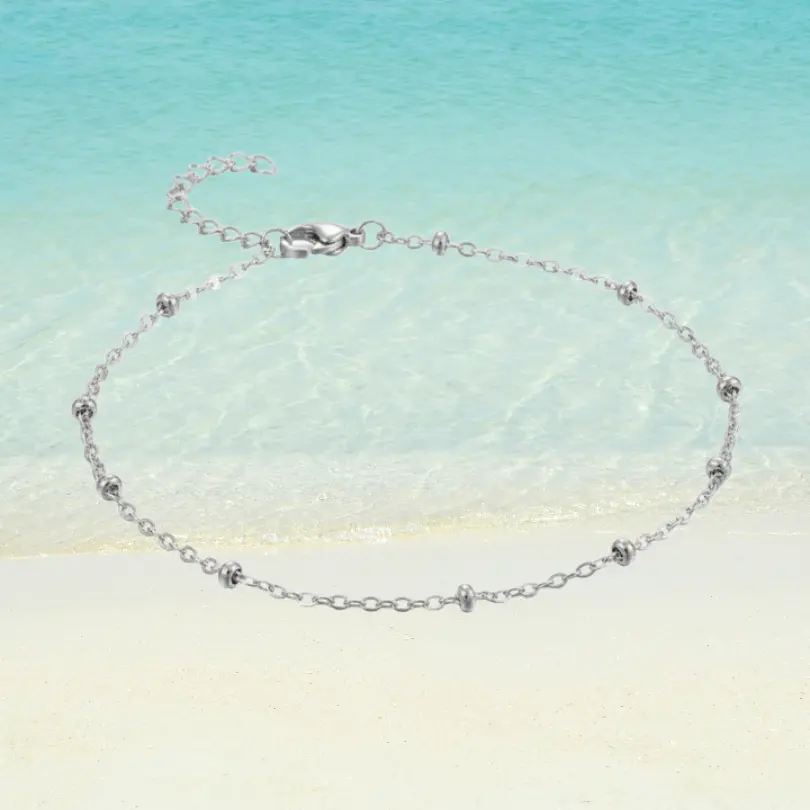 Chaîne de Cheville Perle 8 Chaîne de cheville argentée en acier inoxydable maille forçat avec mini perles argentées intercalées, rallonge fine, fermoir mousqueton, fond plage sable blanc