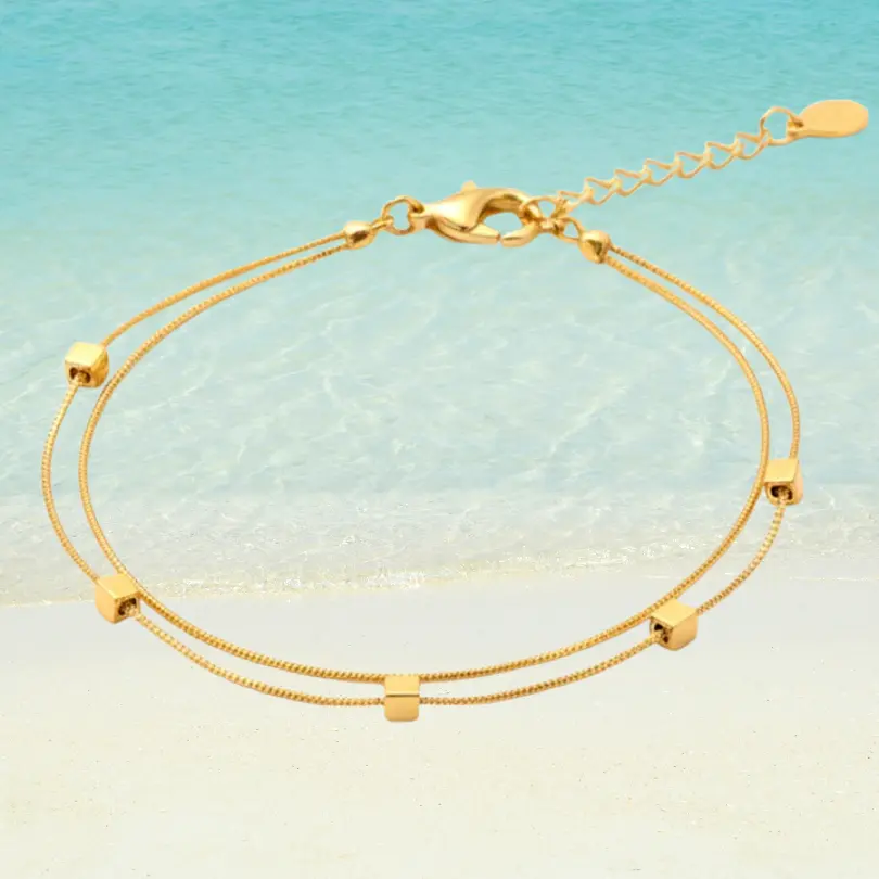 Chaîne de Cheville Perle 6 Chaîne de cheville dorée double rang en acier inoxydable avec perles carrées dorées, maille serpent fine, fermoir mousqueton et rallonge à goutte, fond plage turquoise