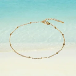 Chaîne de Cheville Perle 14 Chaîne de cheville dorée en acier inoxydable maille forçat avec mini perles dorées intercalées, rallonge barrette, fermoir mousqueton, fond plage turquoise