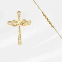 Croix Pendentif 6 Collier croix pendentif doré symbole infini orné de zircons pour femme — pendentif croix religieuse avec nœud infini pavé strass sur chaîne fine dorée, fond blanc épuré