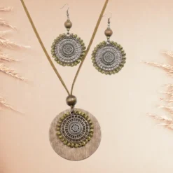Parure Bijoux Bohème Chic 11 Parure bohème avec collier pendentif rond en bois, médaillon métal ajouré et pampilles de perles, accompagnée de boucles d’oreilles ethniques assorties.