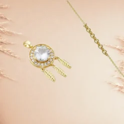 Collier Attrape Rêve 10 Pendentif attrape-rêves doré avec zirconium blanc central, entouré de strass et plumes, sur chaîne dorée